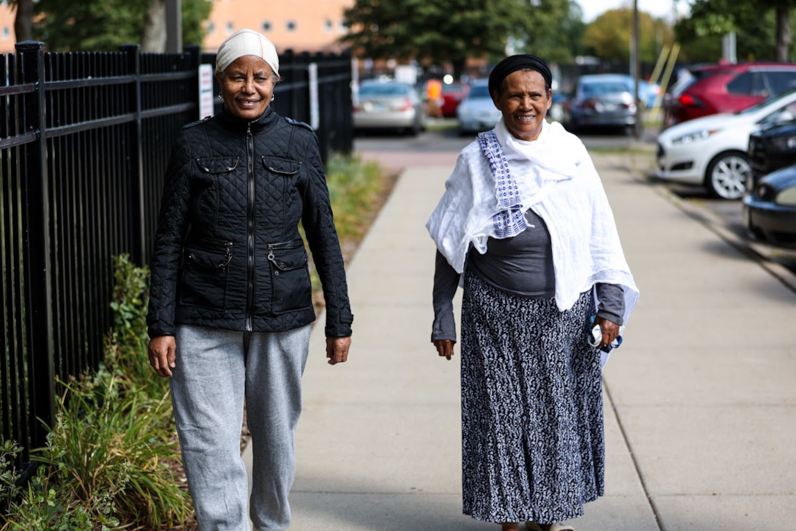 Two older women walking outside on a city sidewalk